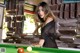 A woman leaning over a pool table with a cue.