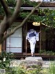 A woman in a kimono standing in front of a house.