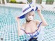 A woman in a blue and white dress and hat in a pool.