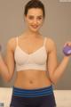 A woman in a white bra top holding two purple dumbbells.