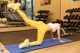 A woman doing a plank on a blue mat in a gym.