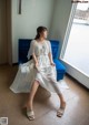 A woman in a white dress sitting on a blue chair.