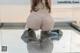 A woman in a pink thong and high heels sitting on a glass table.