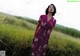 A woman in a purple dress standing in a field.