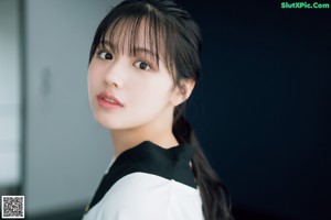 A woman with long black hair wearing a white shirt.