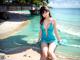 A woman in a blue dress sitting on the beach.