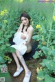 A woman in a white dress sitting in a field of flowers.