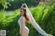 A woman in a white bodysuit standing in a field of tall grass.