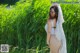 A woman in a white bikini standing in tall grass.