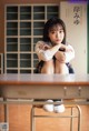 A woman sitting on top of a desk in a classroom.