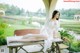 A woman in a white lingerie sitting on a wooden bench.