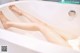 A woman laying in a bathtub with her legs in the water.