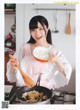 A woman holding a bowl of rice in a kitchen.