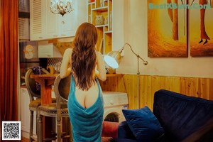 A woman in a blue dress standing in a living room.