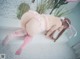 A woman in a pink lingerie and stockings is posing for the camera.