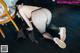 A woman in black stockings and white shoes is bending over on the floor.