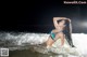 A woman in a blue bikini laying in the ocean.